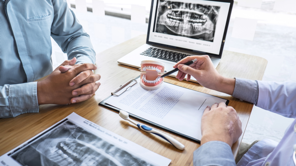 Dentist in Jayanagar explaining oral surgery treatment options using dental models and X-rays during a patient consultation